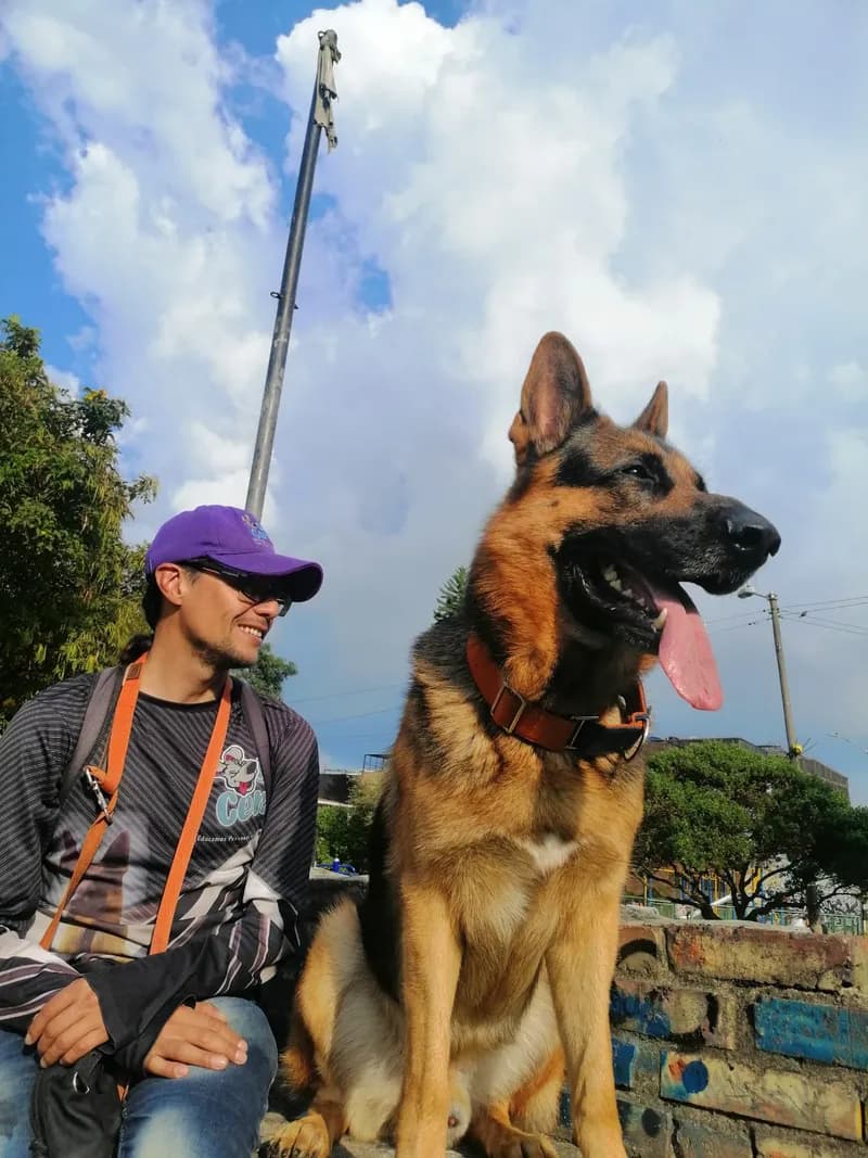 Diego Martínez, adiestrador canino de Rafadogs, sentado al aire libre junto a un pastor alemán.